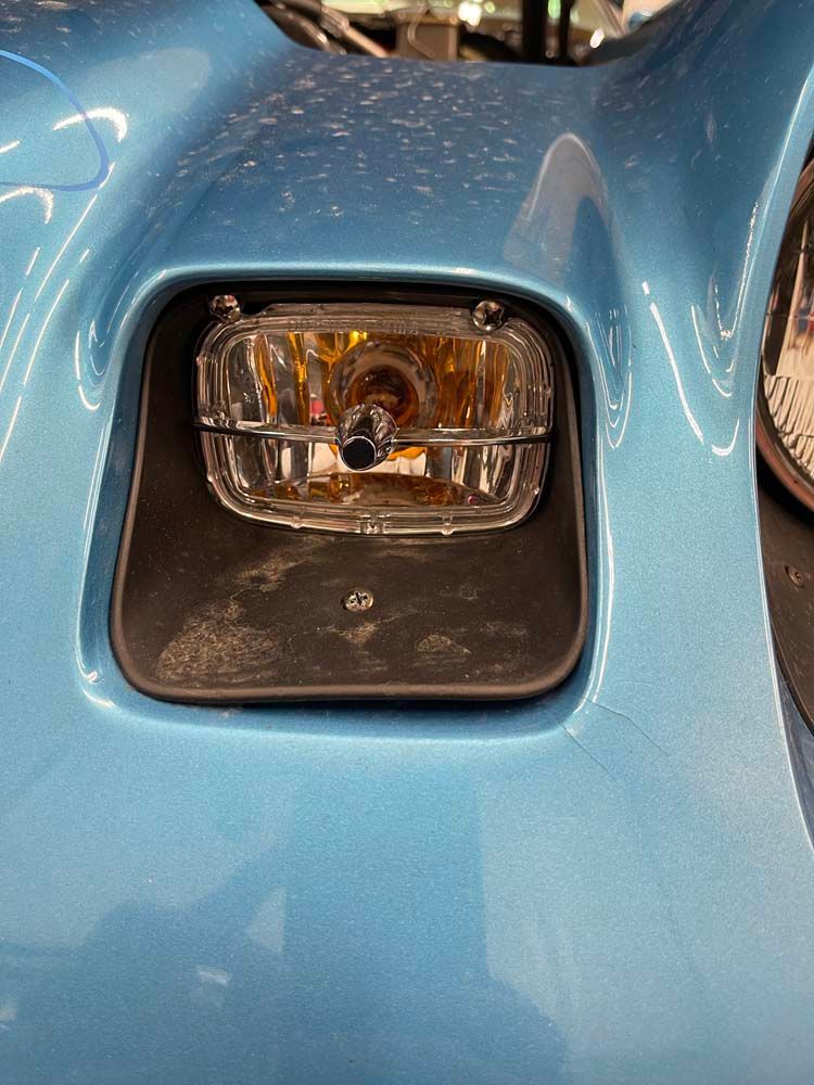 A close up of a headlight on a blue car.