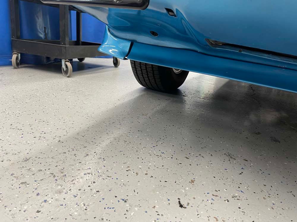 A blue car is parked in a garage next to a cart