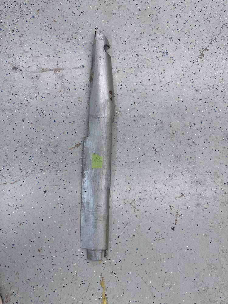 A long piece of metal is sitting on a gray surface.
