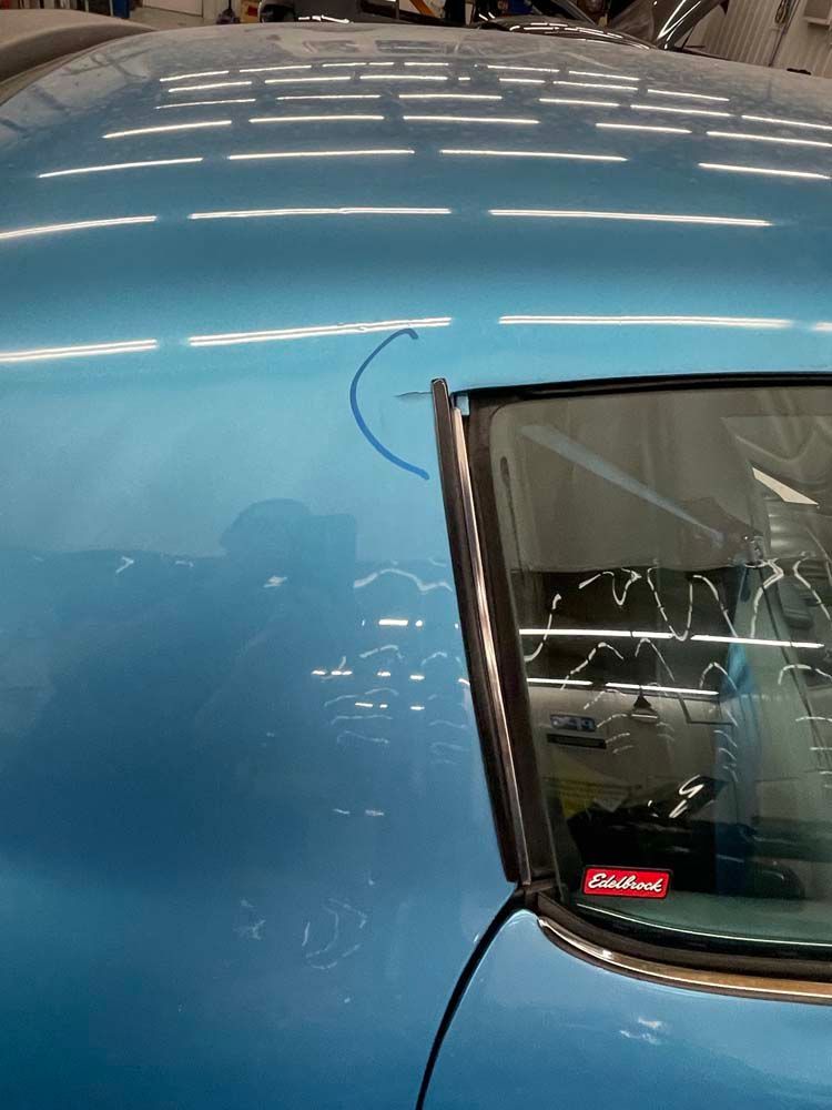 A blue car is parked in a garage with a sticker on the window that says edelbrock.