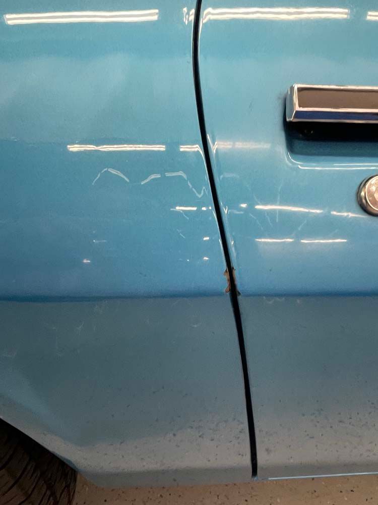 A close up of a blue car door with a chrome handle