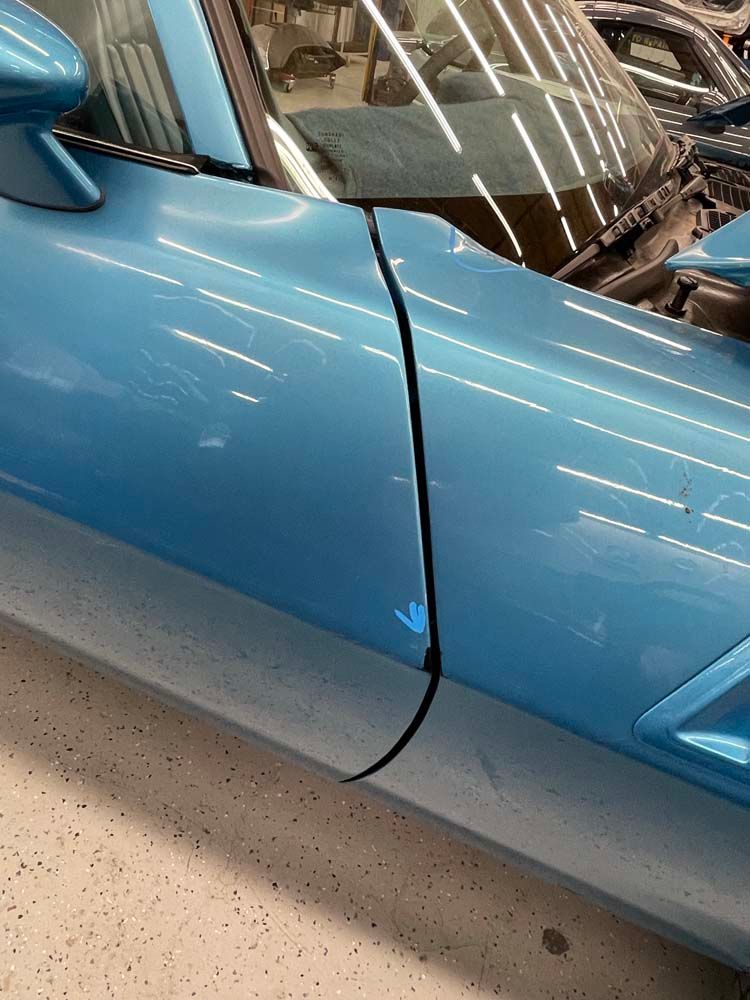 A blue sports car is parked in a garage with the door open.