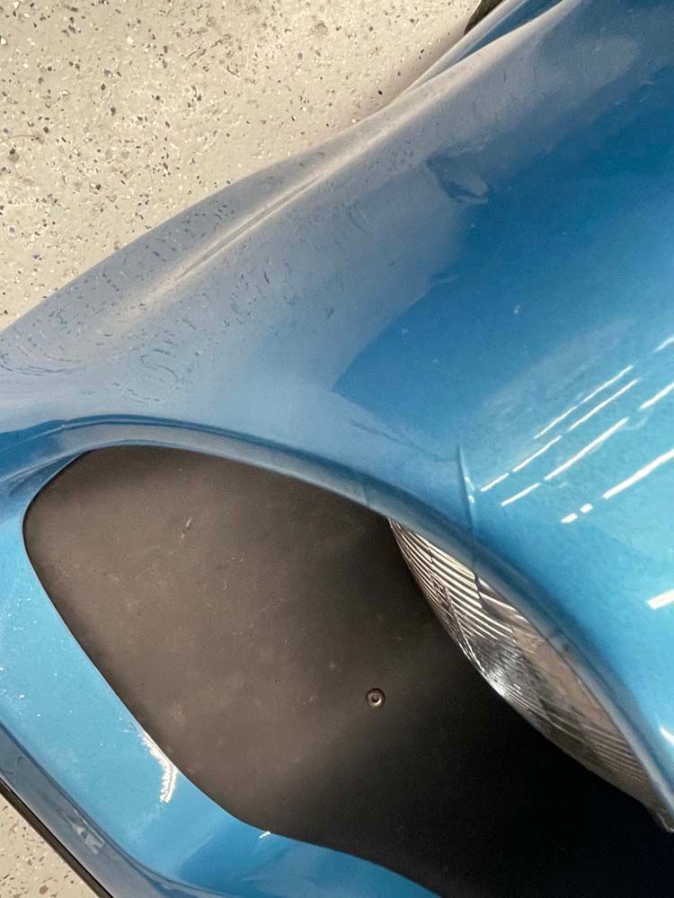 A close up of a blue car 's fender in a garage.