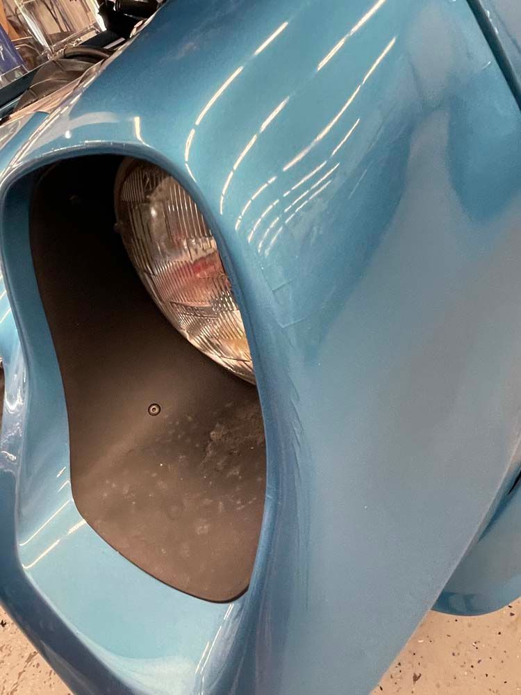 A close up of a blue car 's headlight and fender.