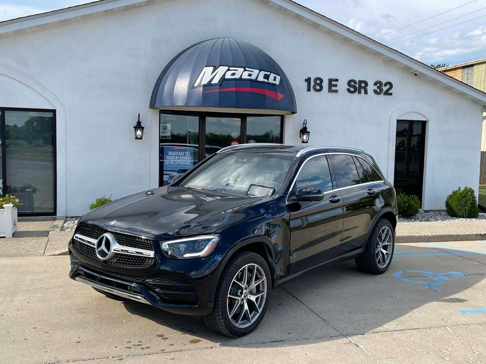 A black mercedes benz glc is parked in front of a car dealership.