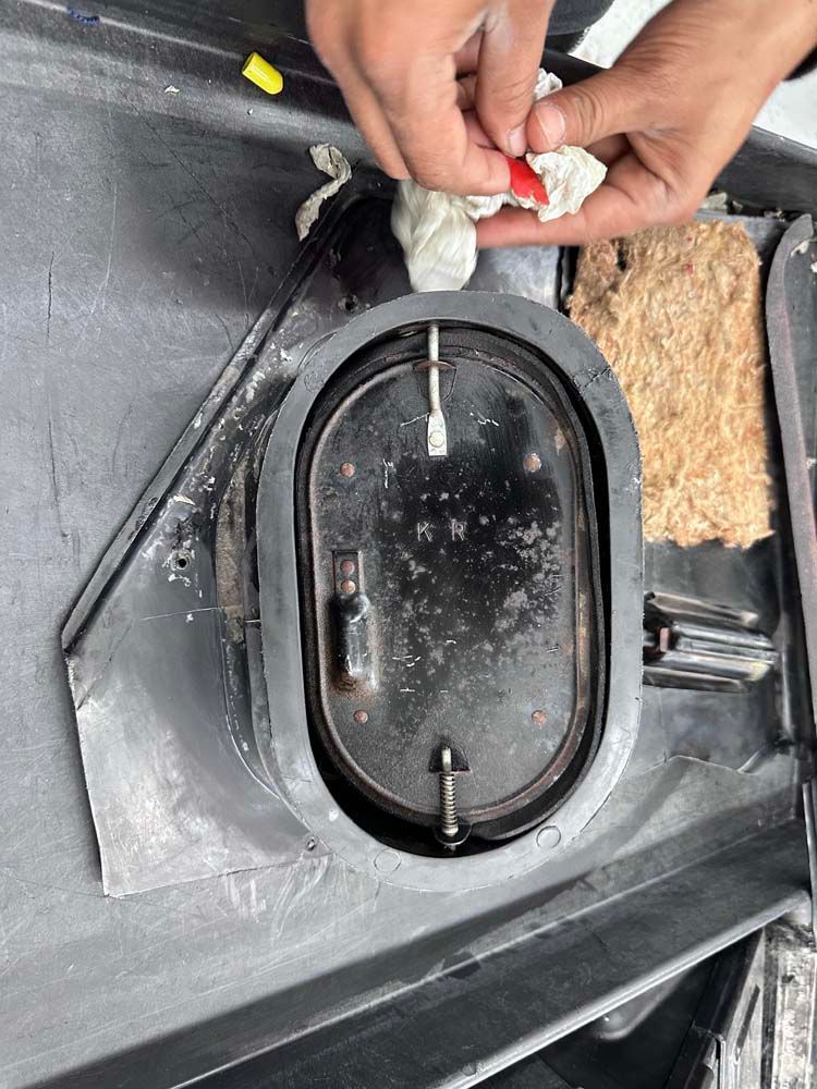A person is cleaning a piece of metal with a cloth.