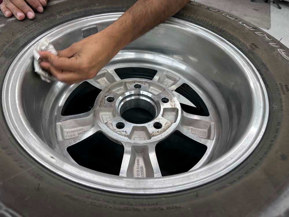 A person is cleaning a tire rim with a cloth.