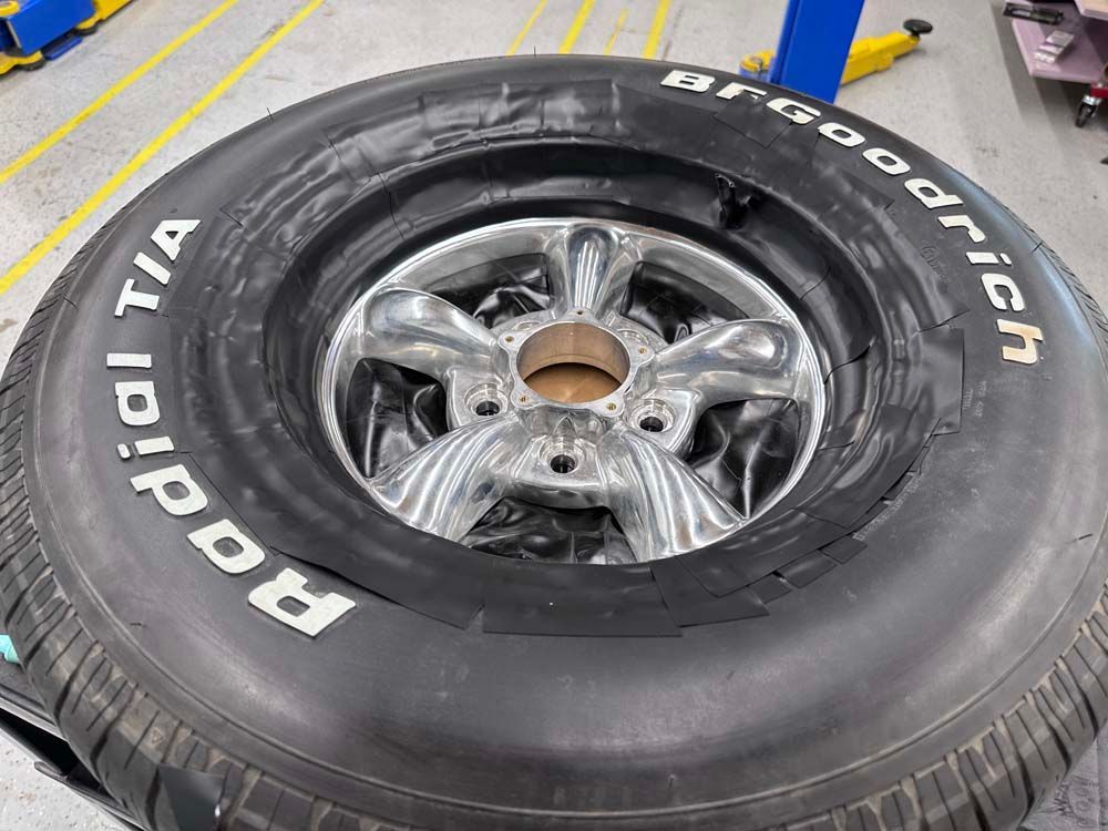 A bfgoodrich tire is sitting on top of a wheel.