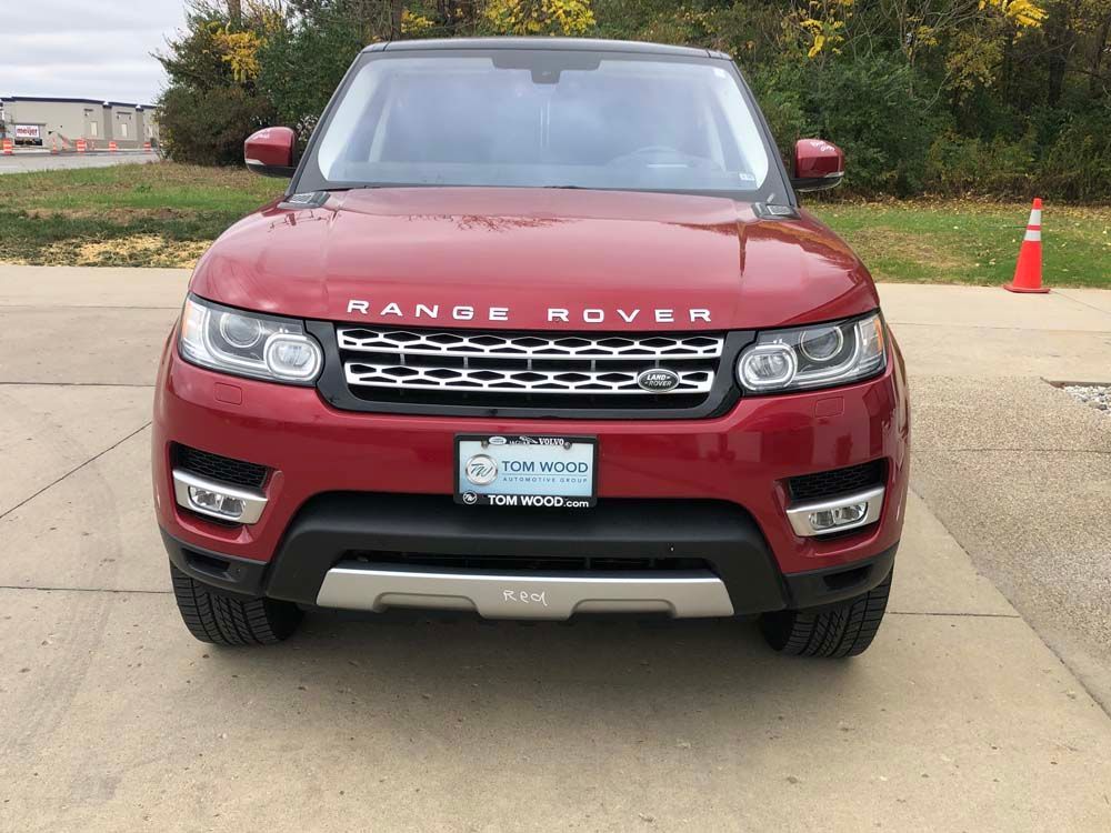 A red range rover sport is parked on the side of the road.