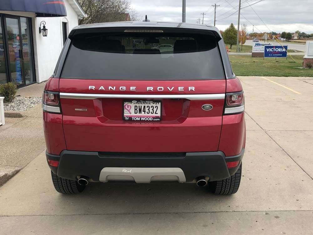 A red range rover sport is parked in a parking lot.