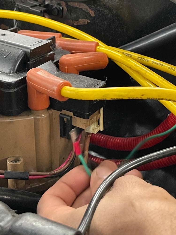 A person is working on a car with yellow wires