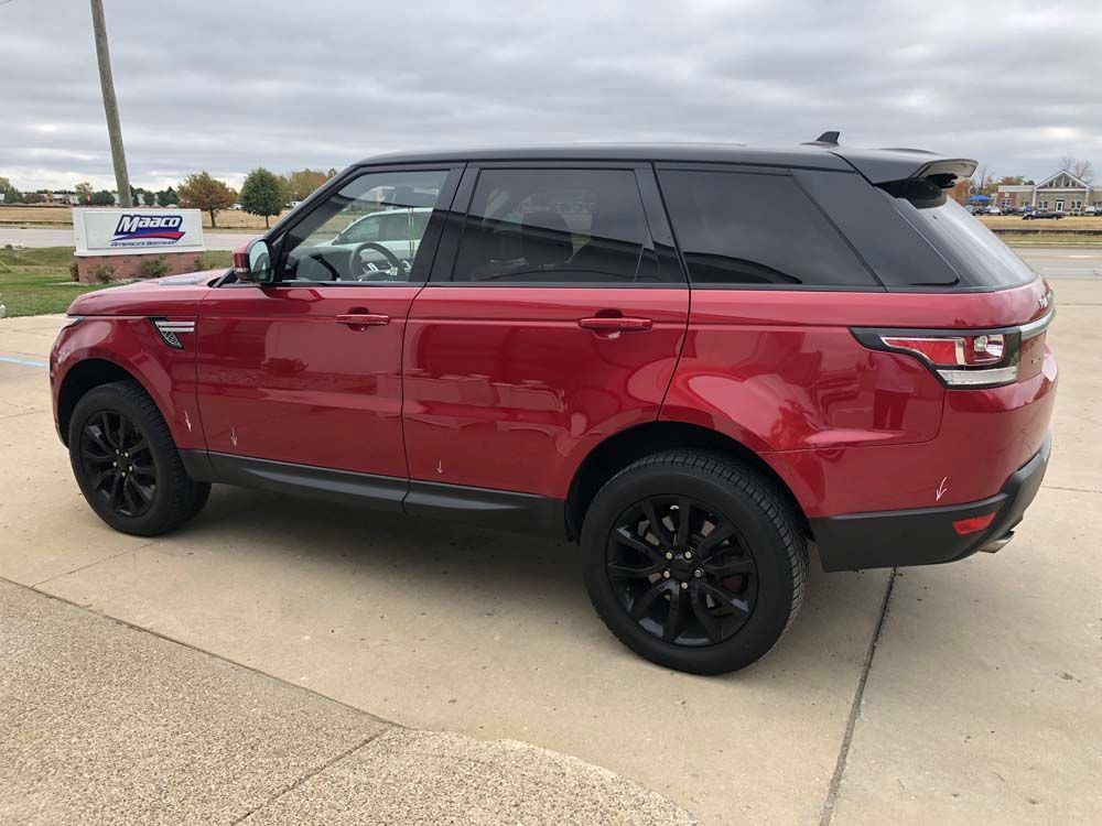 A red range rover sport is parked on the side of the road.