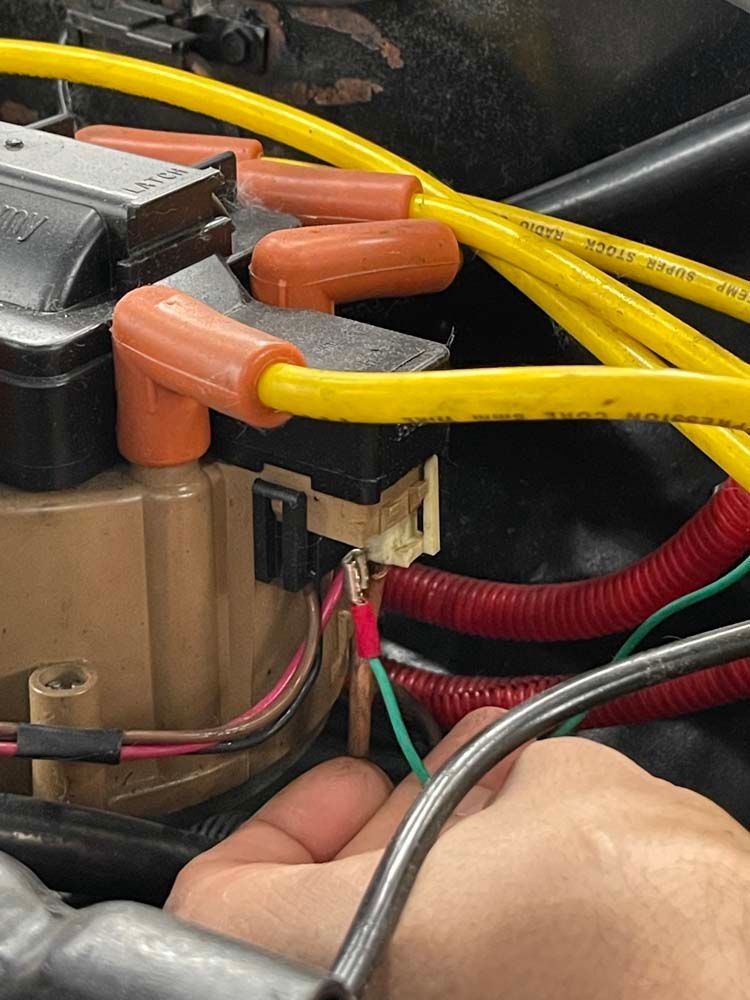 A person is working on a car engine with a wrench.