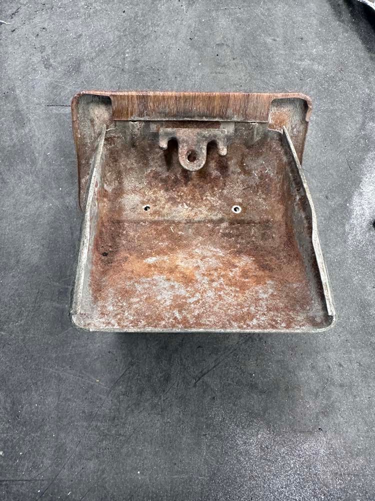 A rusty metal object is sitting on a concrete surface.