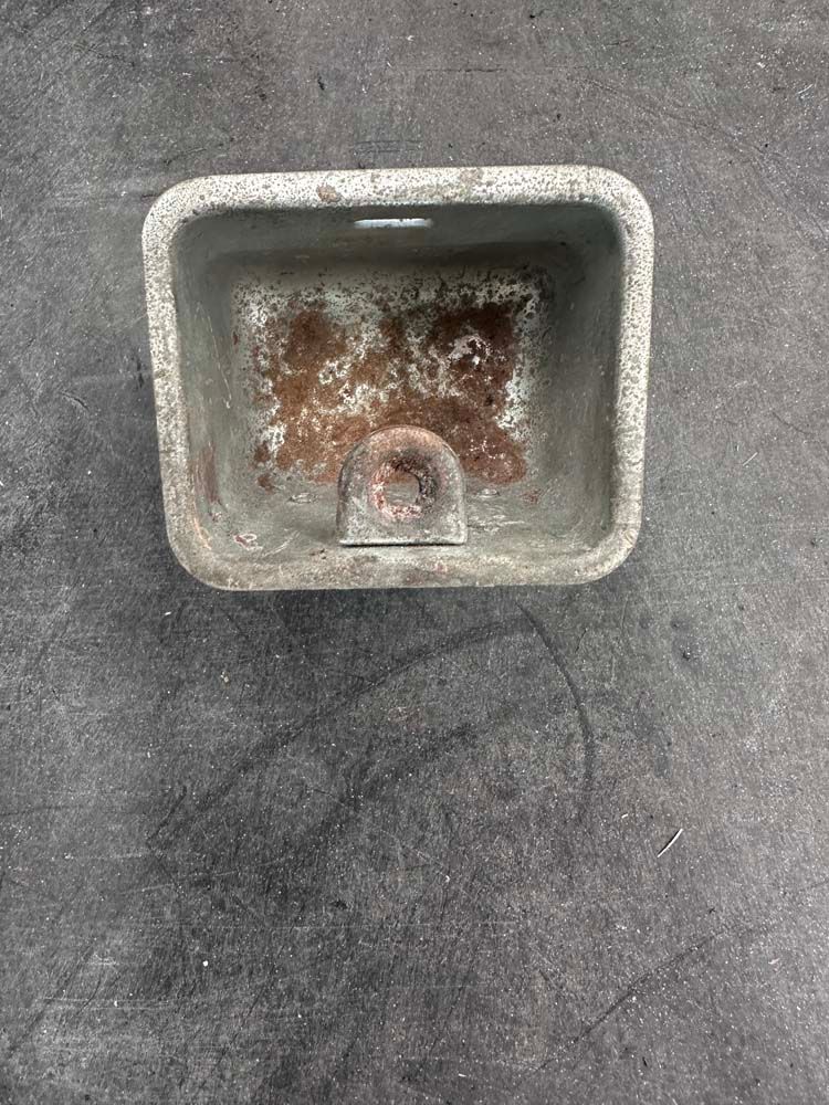 A small sink is sitting on a concrete surface.