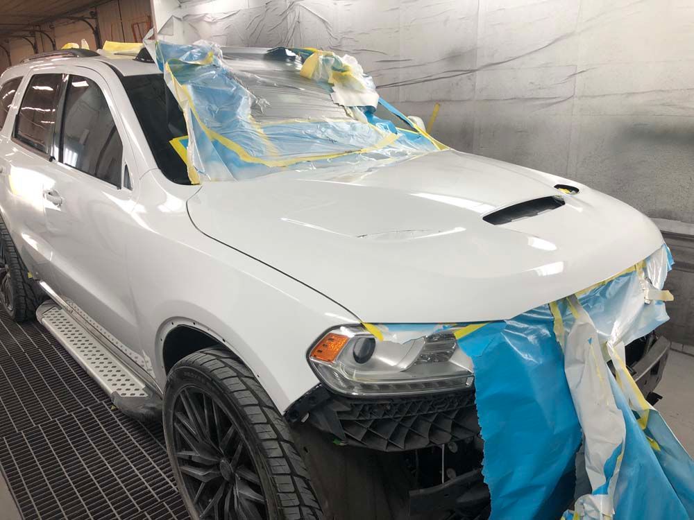A white suv is being painted in a paint booth.