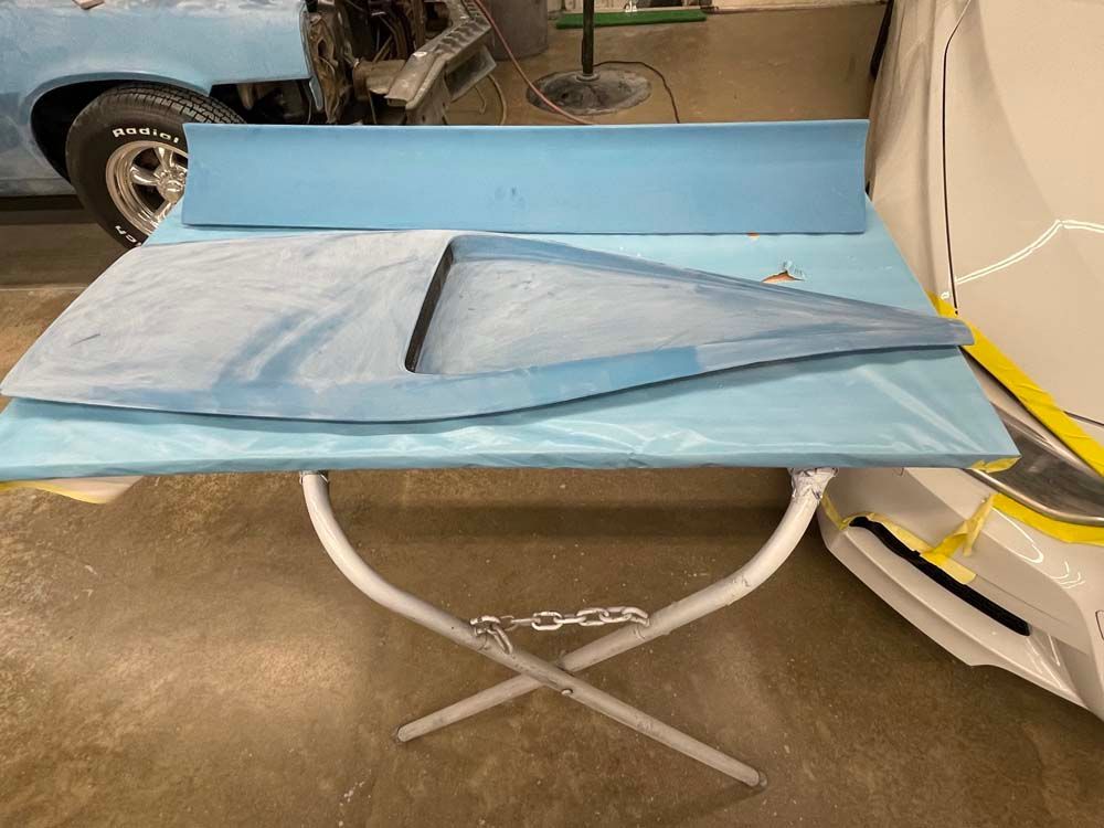 A piece of blue foam is sitting on a table next to a car.