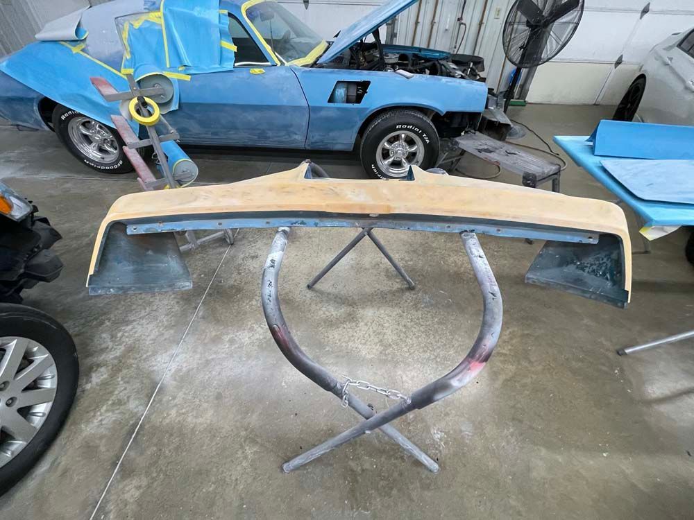 A blue car is sitting in a garage next to a wooden table.