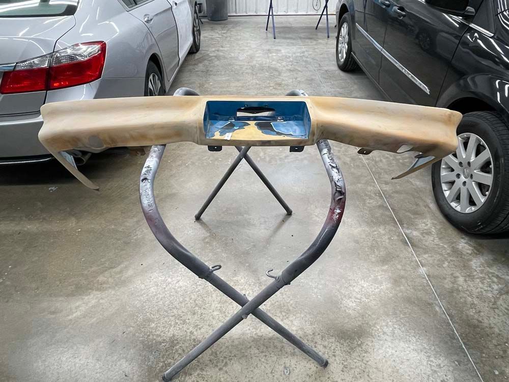 A piece of wood is sitting on a metal stand in front of a car.
