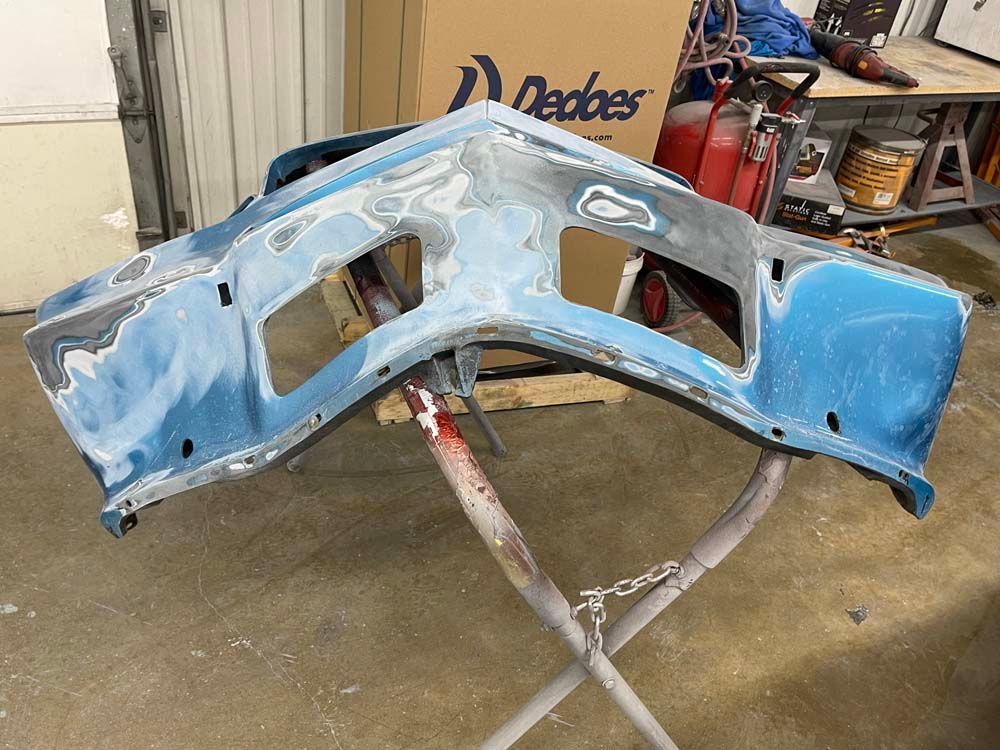 A blue bumper is sitting on a stand in a garage.