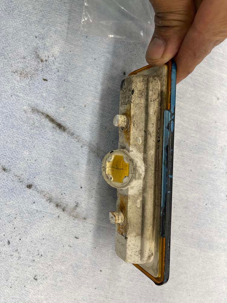 A person is holding a piece of metal on a white surface.