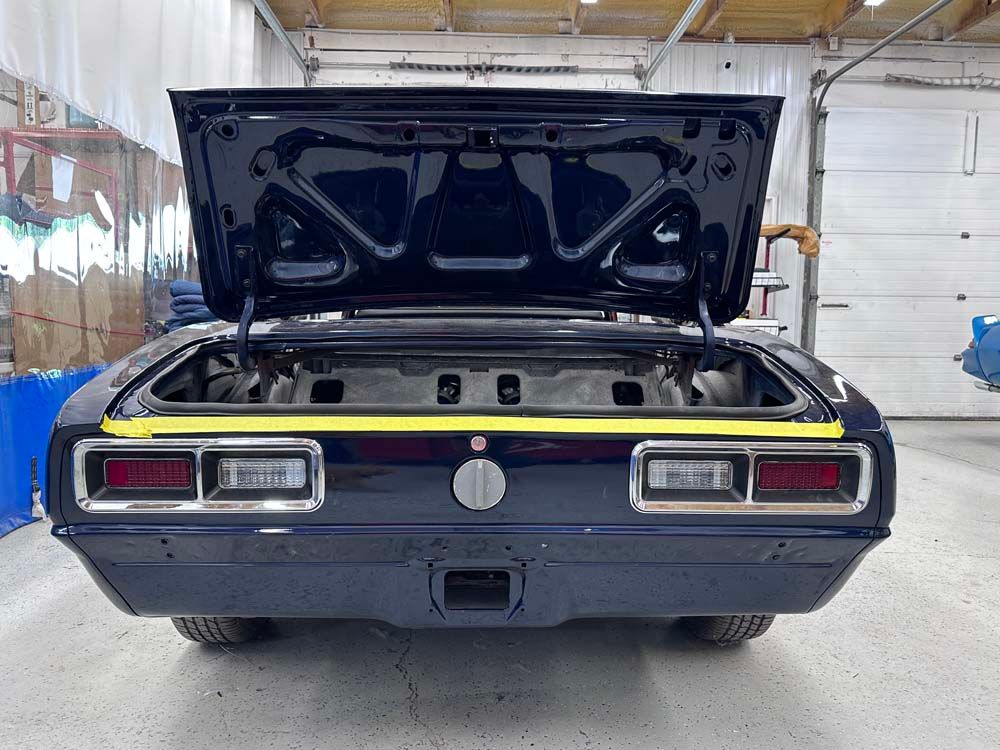 A black car with the hood up is sitting in a garage.