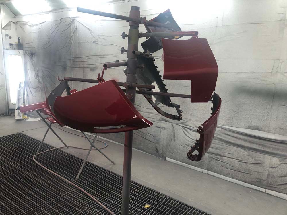 A red car is being painted in a paint booth.