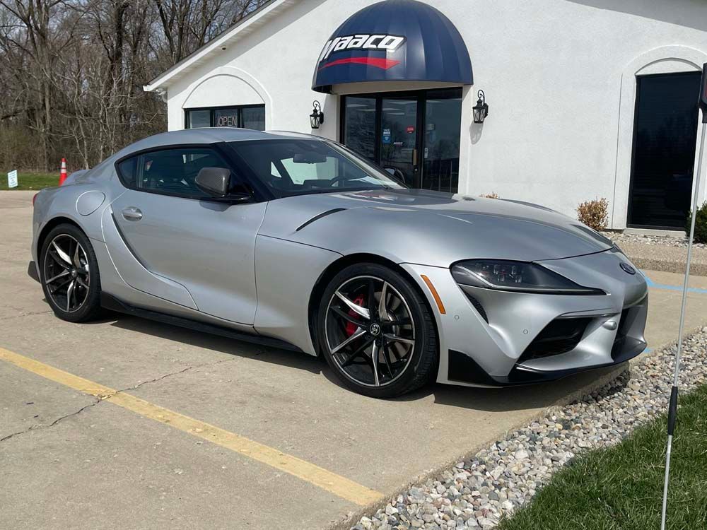 A silver sports car is parked in front of a building.