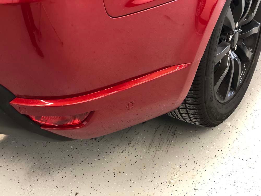 A red car with a black tire is parked in a garage.