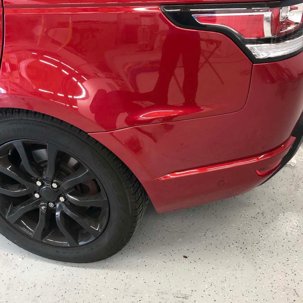 A red car with black wheels is parked in a garage