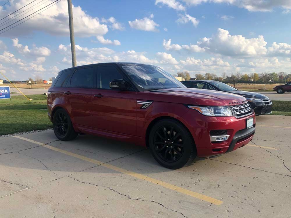 A red range rover sport is parked in a parking lot.
