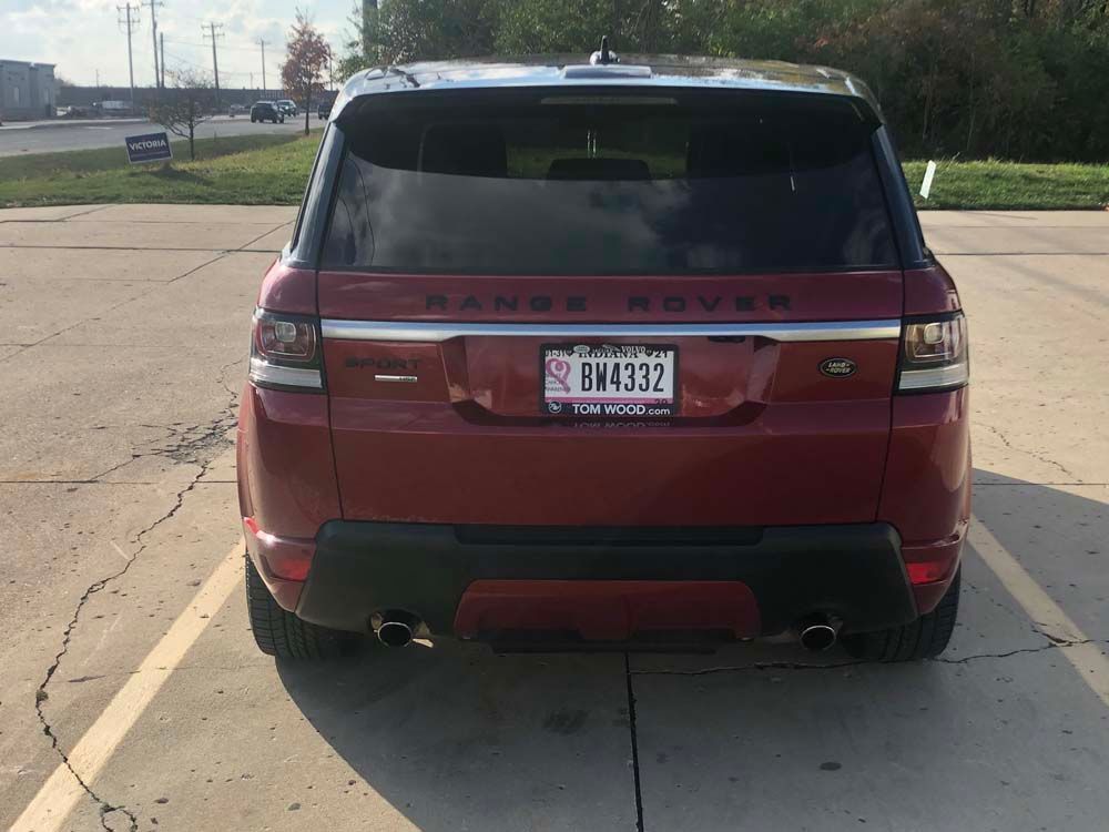 A red range rover is parked in a parking lot