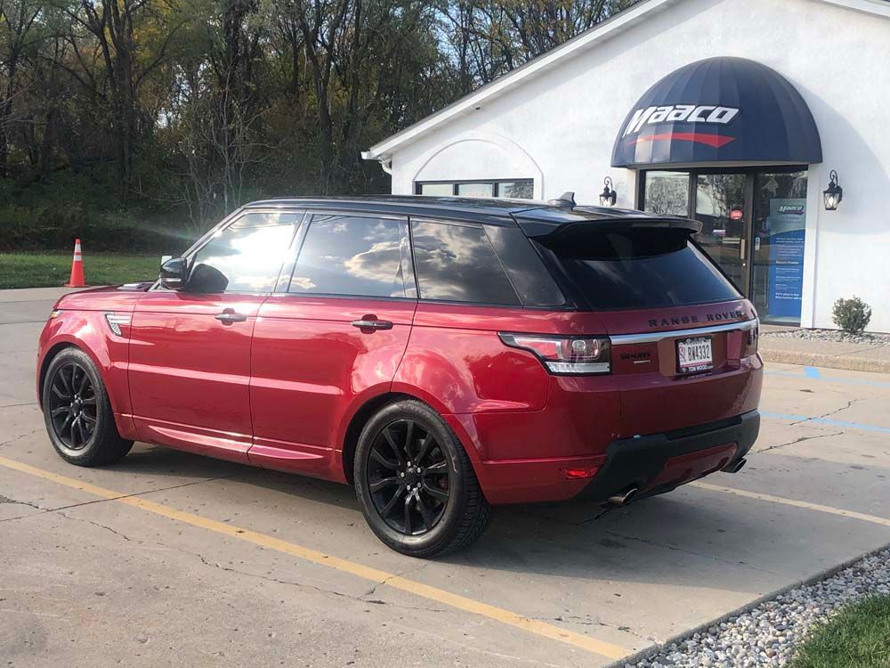 A red range rover sport is parked in a parking lot in front of a building.