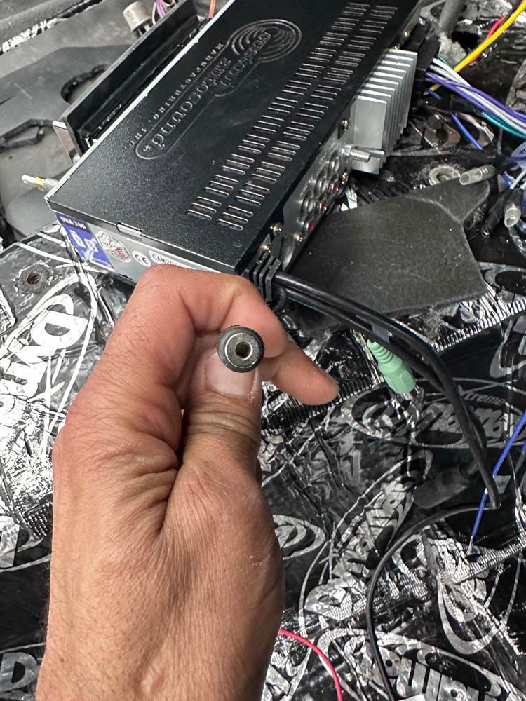 A person is holding a plug in their hand in front of a computer.