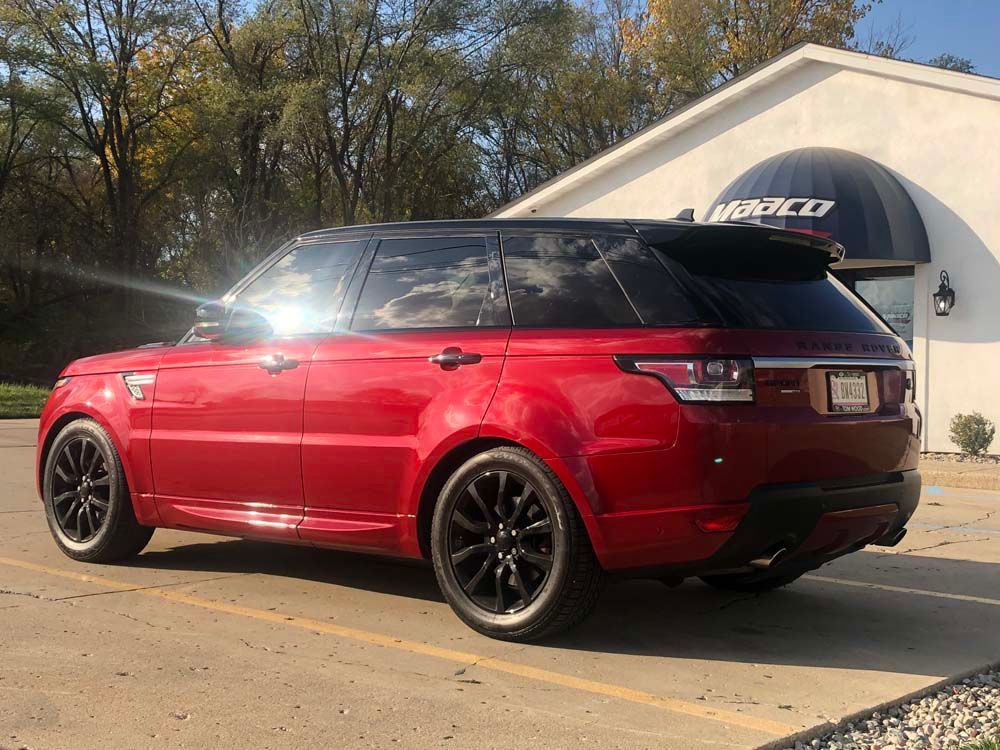 A red range rover sport is parked in a parking lot in front of a building.