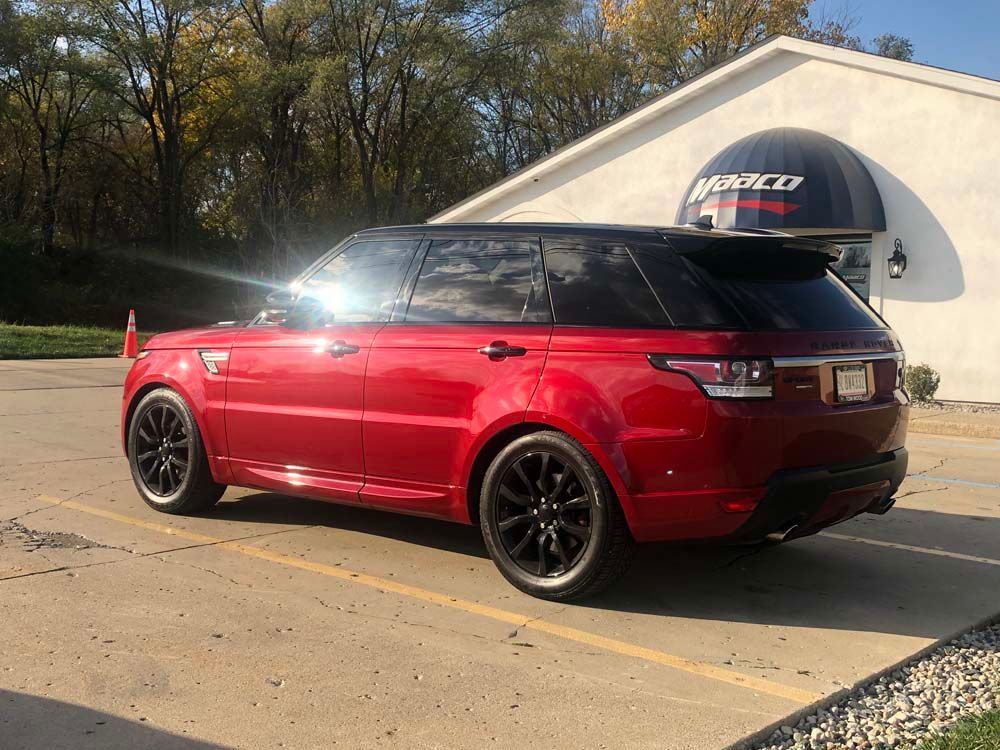 A red range rover sport is parked in a parking lot in front of a building.