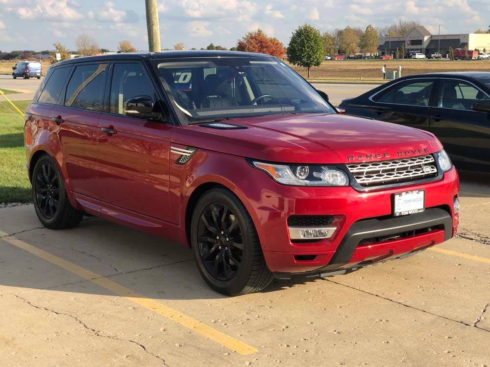 A red range rover sport is parked in a parking lot.
