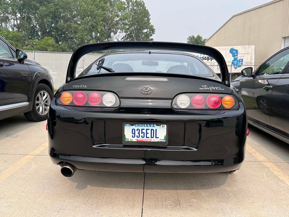 A black car with a license plate that says 935edl is parked in a parking lot.