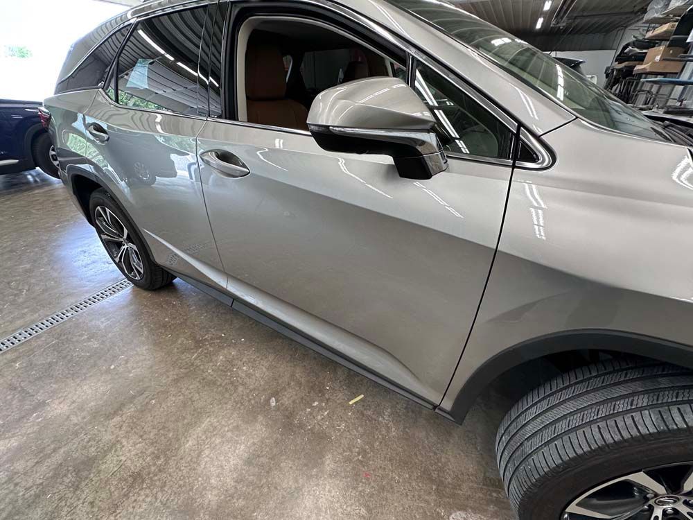 A silver car is parked in a garage next to a blue car.