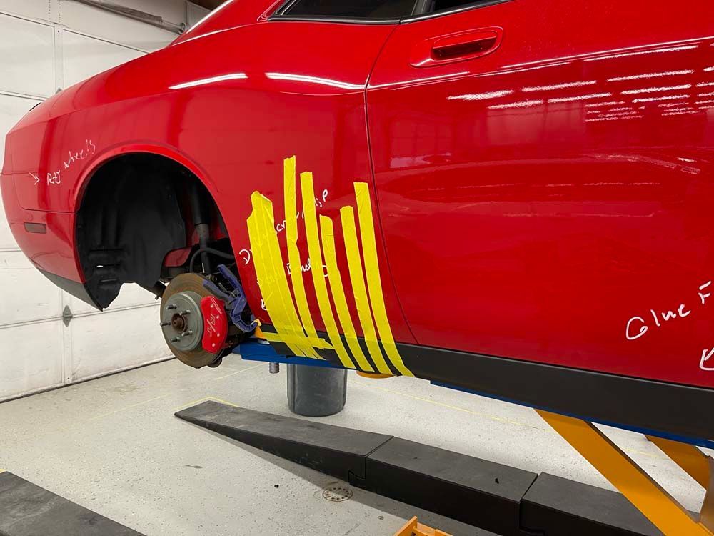 A red dodge challenger is sitting on a lift in a garage