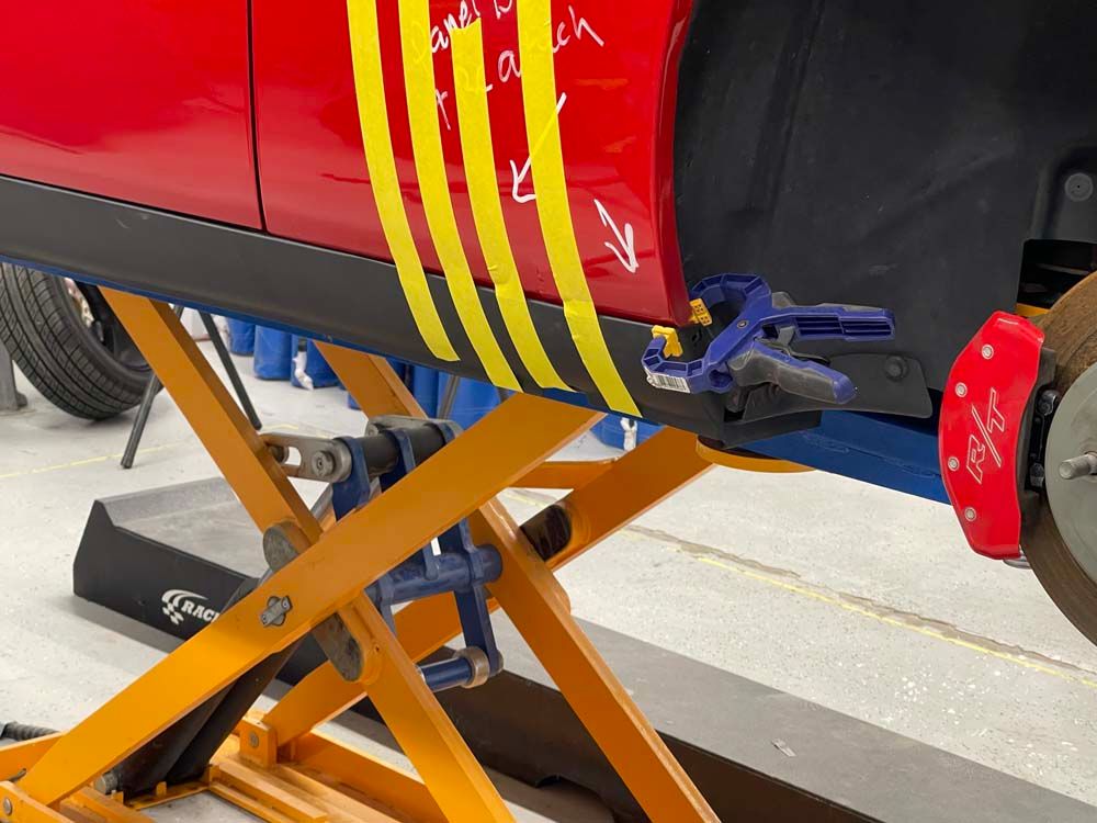 A red car is being lifted on a scissor lift
