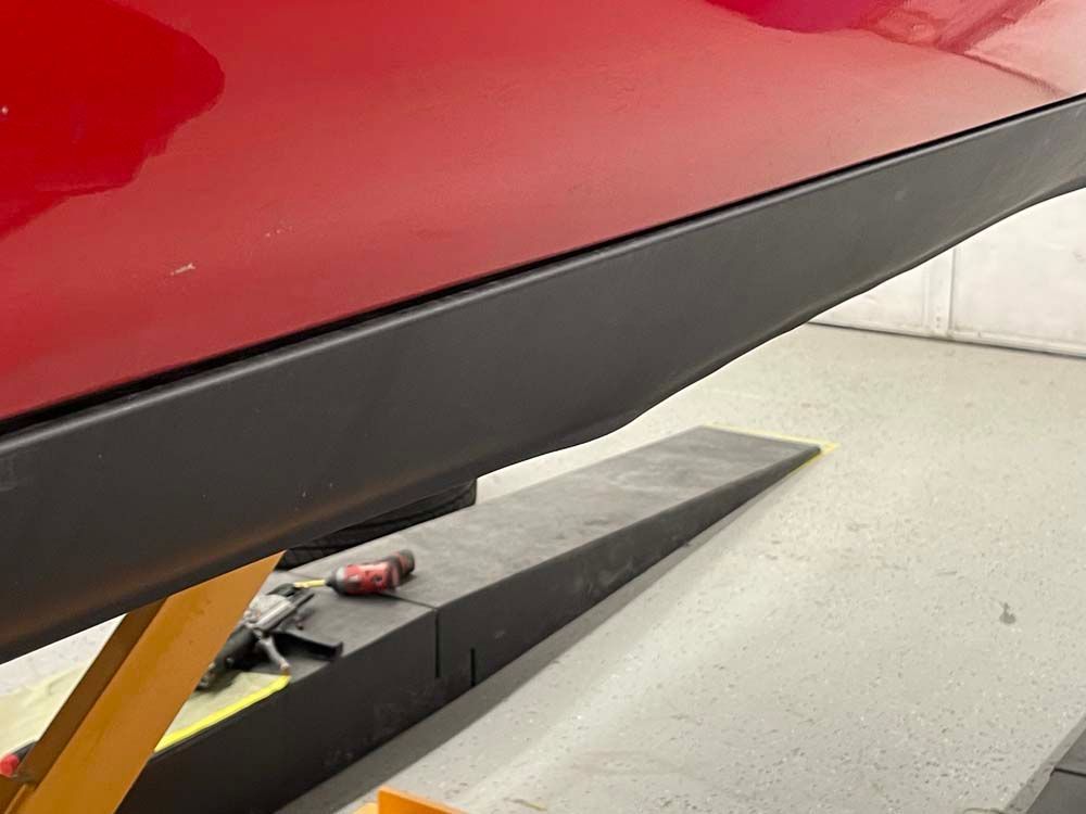 A red car is sitting on a lift in a garage.