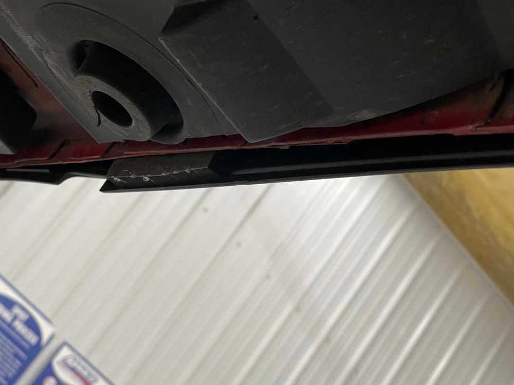 A close up of the underside of a car in a garage.