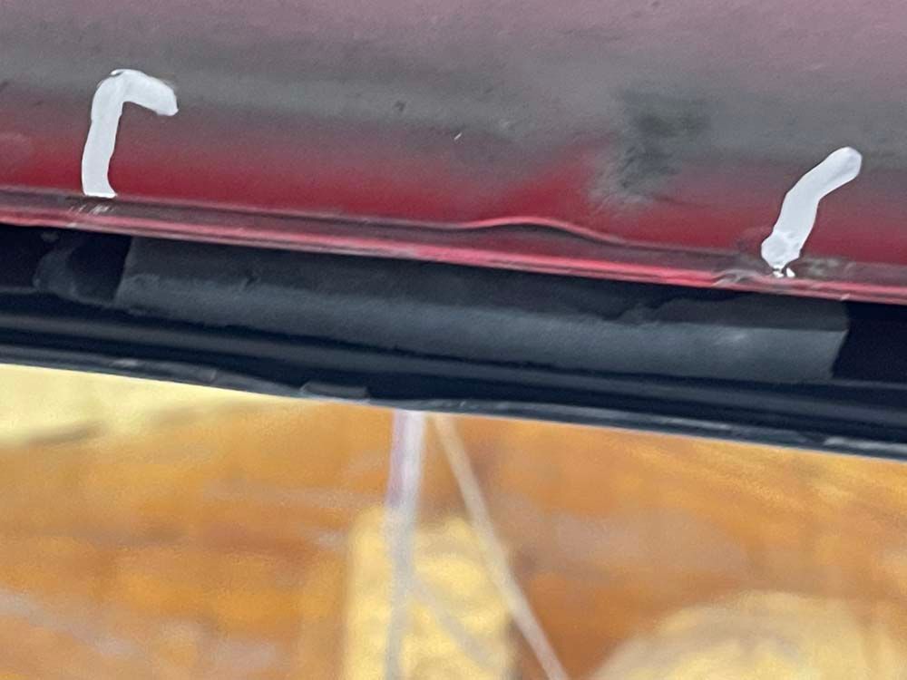 A close up of a red car with a black hose attached to it.