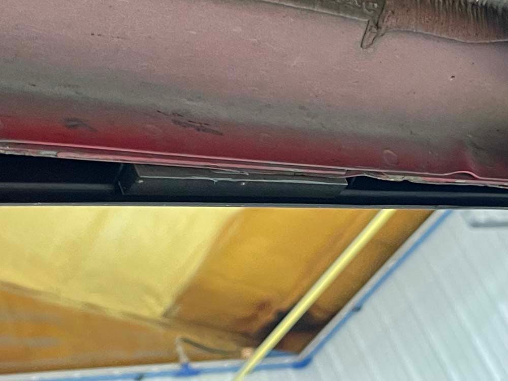 A red car is sitting under a wooden ceiling