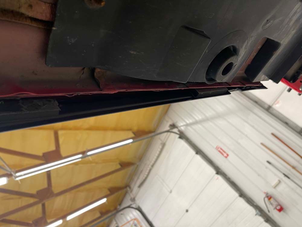 The bottom of a car is shown in a garage