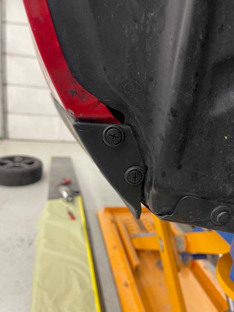 A red car is sitting on top of a yellow lift in a garage.