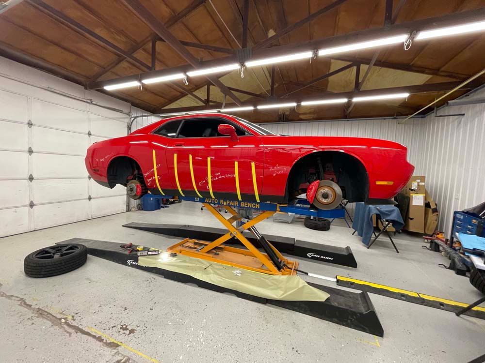 A red dodge challenger is sitting on a lift in a garage.