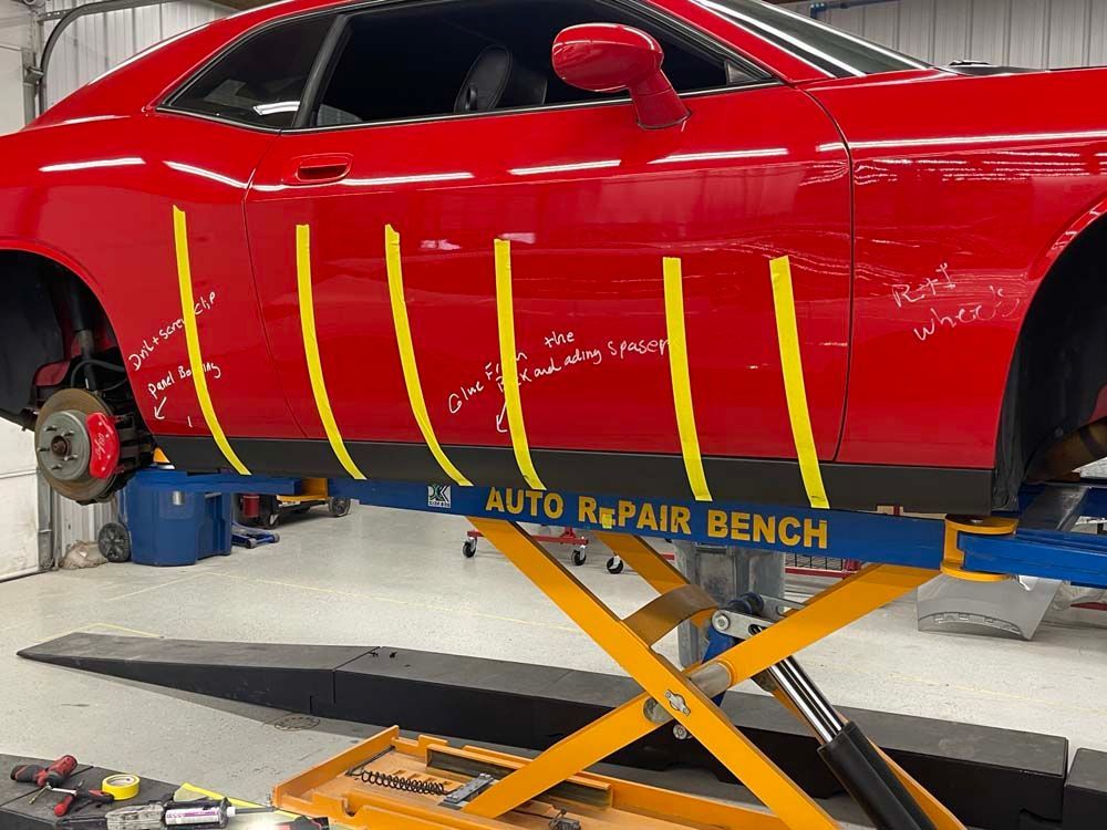 A red car is sitting on an auto repair bench