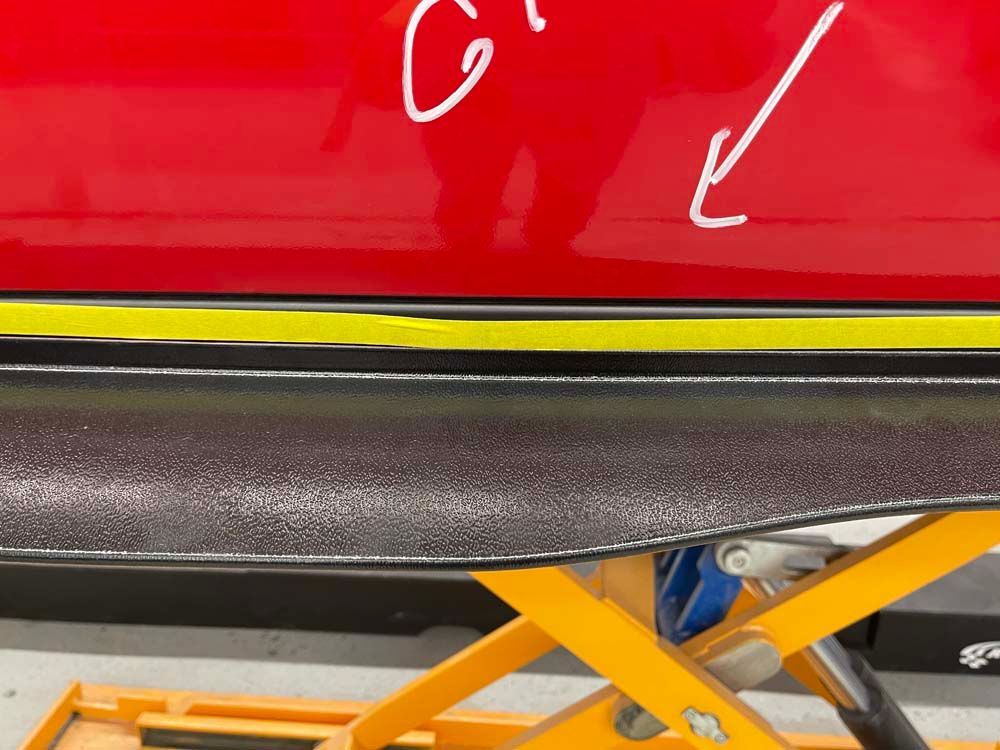 A red car is sitting on a yellow scissor lift.
